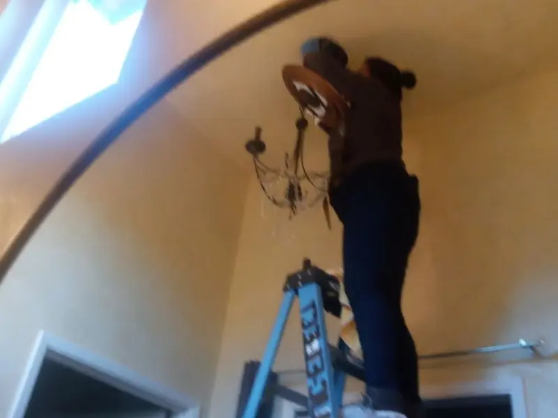 Electrician installing a chandelier in a Benson residence